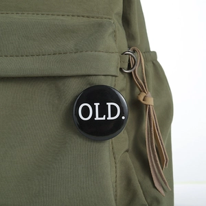 Close-up of military green canvas backpack with black OLD. badge and brown leather fringe