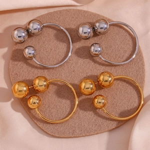 Detail of chunky gold and silver triple bead hoop earrings on soft pink satin fabric