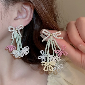 Detailed view of floral tassel earrings with beaded bows and pastel flower pendants