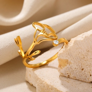 Macro detail of golden tulip ring with sparkling zircon stone on beige stone surface