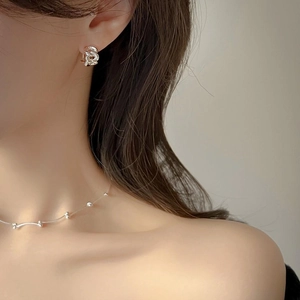 Close-up of minimalist sterling silver chain link earrings and beaded necklace on a model