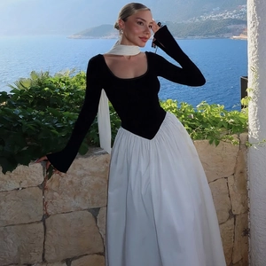 Detail of elegant black and white color block maxi dress with long sleeves and pleated skirt
