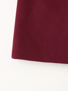 Close-up of the thick burgundy wool fabric texture and hem detail on the loose-fit coat
