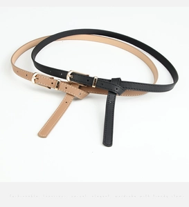 Detail of slim black and khaki PU leather belts with gold buckles on white background
