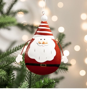 Detail of painted metal Santa ornament hanging on a Christmas tree with bokeh lights