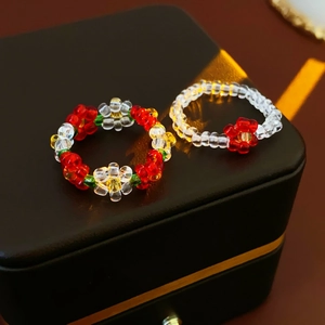 Detail of colorful beaded flower rings on a black leather texture jewelry box surface