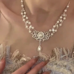 Detail of baroque pearl necklace featuring a floral diamond-set pendant and teardrop pearl