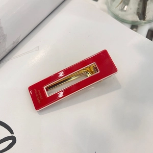 Detail of red handmade hair clip with white border and gold spring clip mechanism