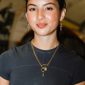 Golden sword earrings and emerald heart key pendant necklace set worn by a model