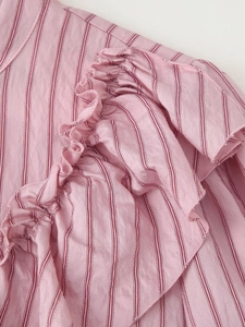 Detailed close-up of pink striped fabric layers and ruffled texture on women shirt