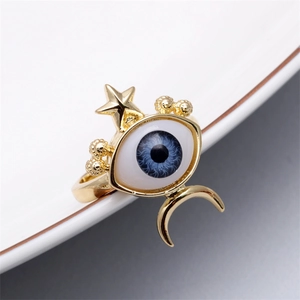 Detail of bohemian gold moon and star ring with blue evil eye on white ceramic