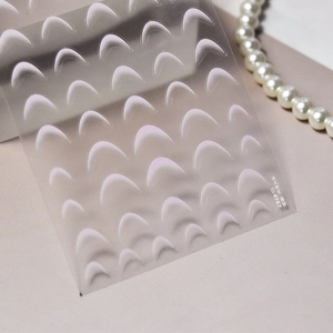 Macro view of white crescent-shaped French tip nail stickers with elegant pearl accent