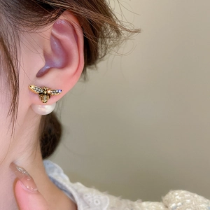 Close-up of model wearing bee earrings with sparkling crystals and a large pearl back