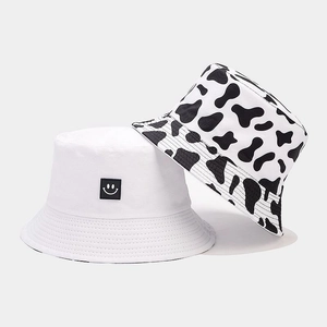 Detail of reversible bucket hat with cow print pattern and smiling face embroidery