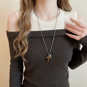 Vintage stainless steel beaded necklace with cross and star pendants on a knit sweater