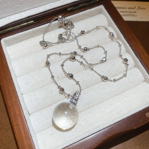 Detailed macro view of a spherical crystal pendant with diamond accents in a wooden box