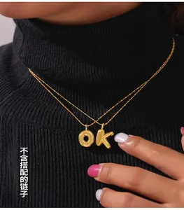 Detail of chubby golden 3D bubble initial pendants O and K on a gold ball chain