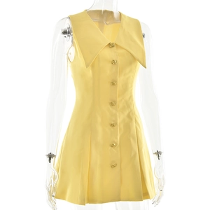 Detail von gelbem ärmellosem Minikleid mit goldenen Knöpfen und Reverskragen in Nahaufnahme