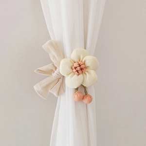 Floral curtain tieback featuring a cream fabric flower with orange details and a bow