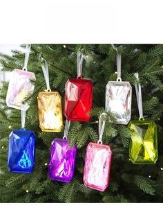 Colorful faceted acrylic gem ornaments hanging on a Christmas tree with warm lights