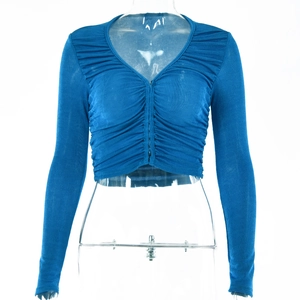 Détail du haut court bleu à manches longues avec col en V, texture plissée et boutons