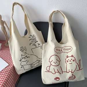 Detail view of cream canvas tote bag with cute cartoon cat illustration and lettering