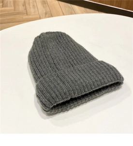 Dettaglio del berretto in maglia grigia con trama in lana spessa e risvolto elasticizzato