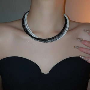 Detailed view of layered seed bead necklace in black and white on model neck