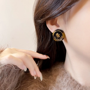 Détail d'une boucle d'oreille ronde en résine vintage avec cheval à bascule doré et ambre