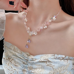 Close-up of pink and purple crystal flower necklace with tassel worn by model