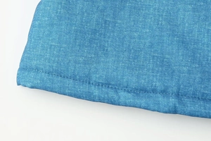 Nahaufnahme der blauen Denim-Stofftextur und präzise Nähte am Ärmelsaum der Jacke