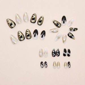 Detail view of handmade press-on nails with dark totem starfish and golden glitter patterns