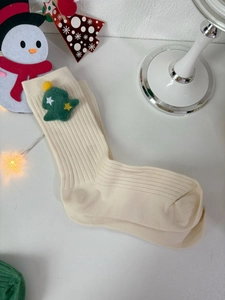 Detail of cream cotton Christmas sock with green felt tree applique and soft pom poms