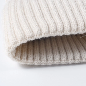 Winter knitted warm beanie with ribbed texture and pompom detail in cream white color