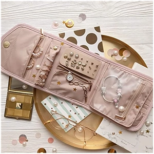 Pink foldable jewelry organizer pouch flat lay with rings, earrings, and necklace compartments