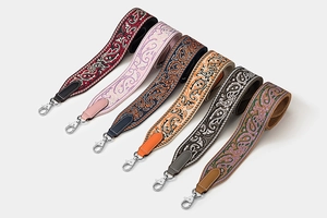 Close-up of six colorful patterned woven bag straps with leather ends and metal hooks