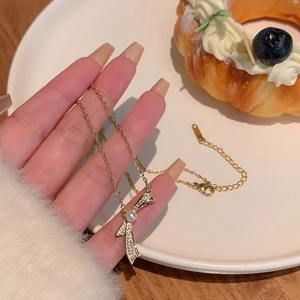 Detail of gold bow necklace with white pearl and micro-inlaid zircons on a delicate chain