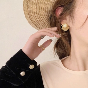 Elegant gold geometric earrings with cream pearls and matching ring on model