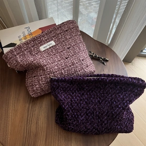 Close-up of pink and purple woven tweed makeup bags with simple wish label on a table