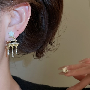 Close-up of golden Christmas tree earrings with spiral rhinestones and tassel chains