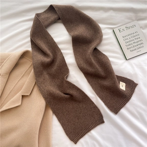 Detailed texture of a dark brown knitted scarf with ribbed edges on a wool coat