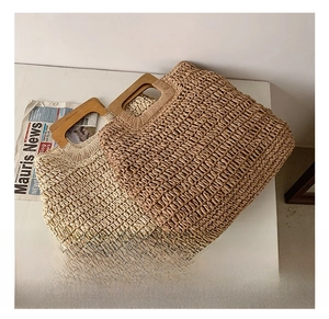 Detail of hand-woven straw beach bags with rectangular wooden handles in beige and brown