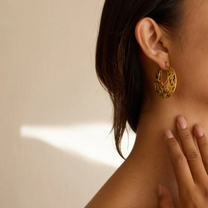Détail de motifs en dentelle ajourée en or 18 carats sur boucles d'oreilles créoles