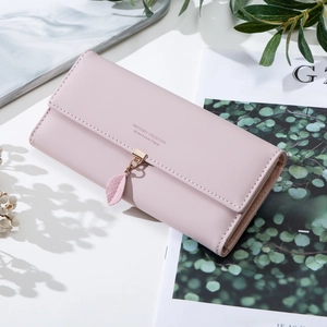 Elegant long pink faux leather wallet for women with leaf pendant on marble background