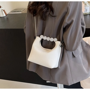 Close-up of a white lychee grain leather mini bag with pearl handle and chain strap