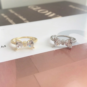 Close-up of bow knot rings featuring triangle zircon stones and micro-paved silver bands