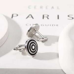 Detailed view of silver round cufflinks with black circular patterns on an open magazine