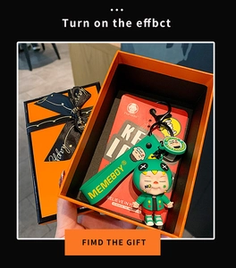 Cartoon figure keychain in orange gift box with decorative happy printed ribbon
