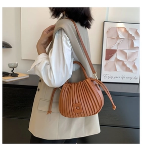 Close-up of brown pleated bucket bag with round handle and drawstring detail