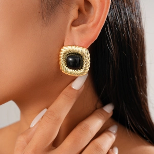 Detail of vintage square gold earrings with twisted texture and black stone inlay
